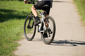 Fototapeta premium a cyclist rides on an asphalt road during the day, close-up