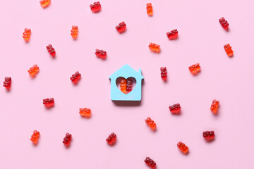 Sweet jelly bears and figure of house on pink background
