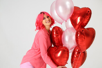 Stylish woman with bright hair and air balloons on light background. Valentine's Day celebration