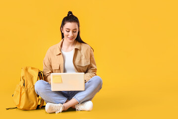 Portrait of beautiful female student with laptop on color background