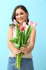 Woman with creative makeup and bouquet of beautiful tulips on blue background. International Women's Day