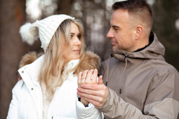 Portrait of happy smiling young couple in casual upper garments stand meeting eyes, holding hands, showing wedding ring.
