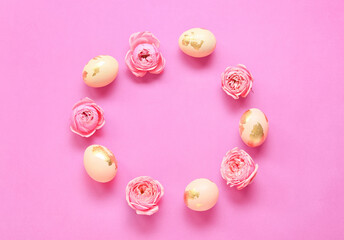 Frame made of Easter eggs and flowers on pink background
