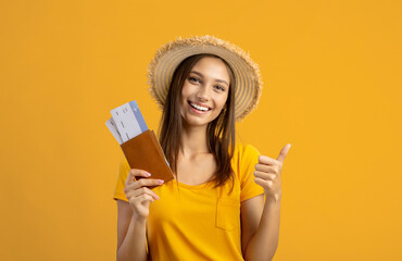 Smiling woman holding passport with tickets, showing thumb up