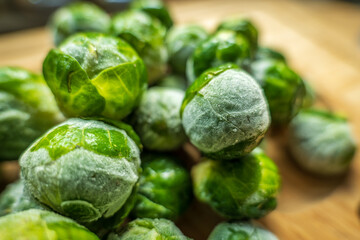 frozen frosty brussels sprouts on wooden plate closeup