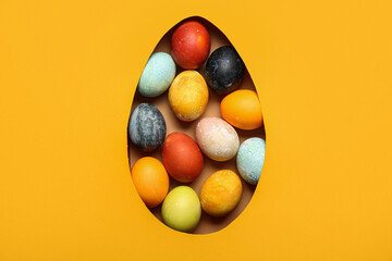 Colorful Easter eggs visible through hole in paper, top view