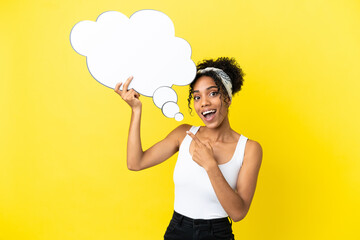 Young african american woman isolated on yellow background holding a thinking speech bubble with surprised expression
