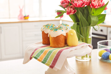 Fototapeta na wymiar Stand with Easter cakes and decor on counter in kitchen, closeup