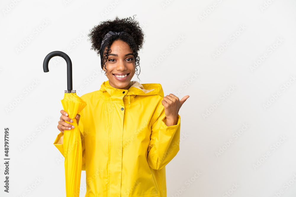 Canvas Prints Young woman with rainproof coat and umbrella isolated on white background pointing to the side to present a product