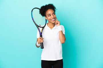 Young tennis player woman isolated on blue background thinking an idea while looking up