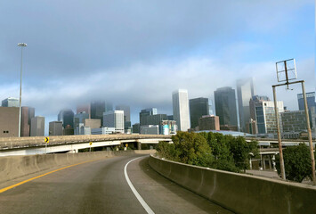 Fototapeta na wymiar Downtown Houston skyscrapers in white fluffy clouds on clear blue sunny day, shot from freeway