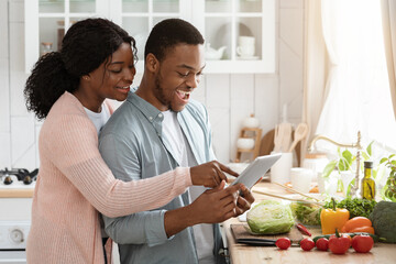Online Recipe. Cheerful Black Couple Using Digital Tablet In Kitchen While Cooking