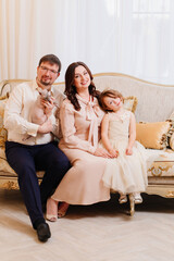 family in classic clothes with a cat of the sphynx breed on a retro sofa.