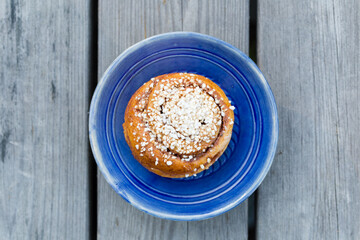 cinnamon bun on a blue plate on wooden backgorund