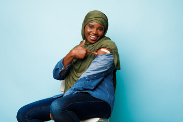African Muslim Woman Showing Vaccinated Arm Gesturing Like, Blue Background