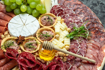 Antipasto platter cold meat plate with grissini bread sticks, prosciutto, slices ham, grapes, jamon...