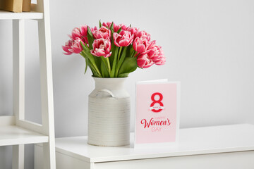 Beautiful bouquet of fresh flowers with greeting card on table in room. International Women's Day celebration