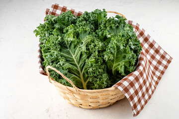 Kale cabbage in a wicker basket on a light table.