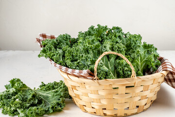 Fresh green kale in a wooden wicker basket. Gray background. Fresh greens. Super food.