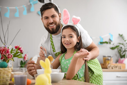 Cute little girl with her father cooking in kitchen on Easter day