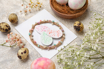 Beautiful composition with greeting card, Easter eggs and flowers on grey background, closeup