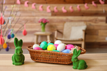 Fototapeta na wymiar Basket with Easter eggs and rabbits on table