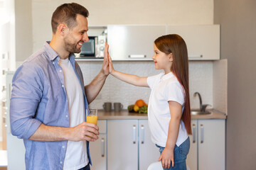 Fototapeta premium Happy Dad And Little Daughter Giving High-Five Standing In Kitchen