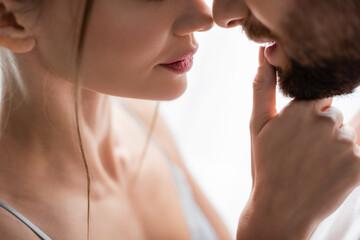 cropped view of woman with closed eyes touching lip of bearded man.