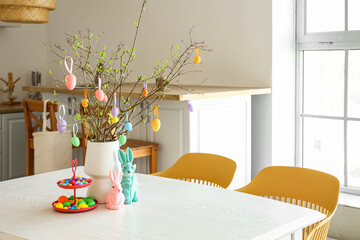 Stand with Easter eggs and decor on dining table in kitchen