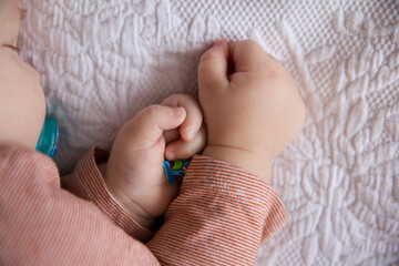 The wounded finger of the child is bandaged with a playful band-aid. Cute baby with a pacifier sleeps soundly in the crib