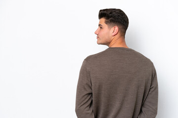 Fototapeta premium Young handsome caucasian man isolated on white bakcground in back position and looking back