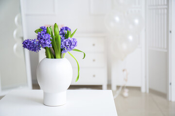 Vase with flowers on table in light room