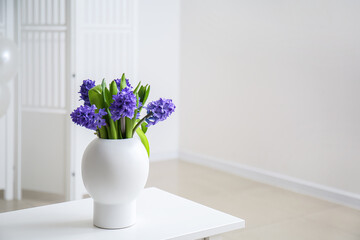 Vase with flowers on table in light room