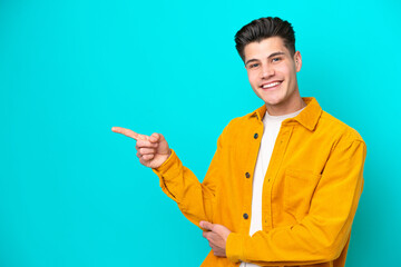 Young handsome caucasian man isolated on blue bakcground pointing finger to the side