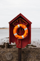 Verical depiction of an orange swimming ring near the empty beach