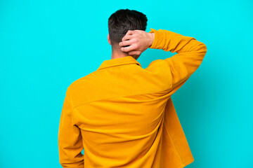 Young handsome caucasian man isolated on blue bakcground in back position and thinking