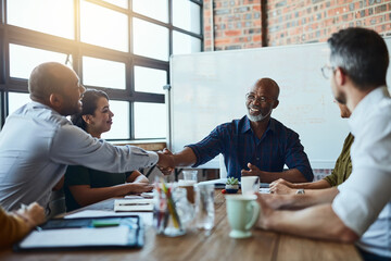 Its settled then. Cropped shot of a group of business colleagues in the office shaking hands in agreement on a certain idea.