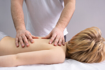 The osteopath works with the spine. A teenage child lies on a couch in front of a doctor. A chiropractor examines the spine. Posture correction