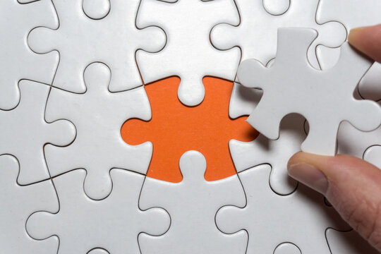 Hand h&auml;lt fehlendes wei&szlig;es Puzzle Teil in der Hand - das Puzzle hat einen Textfreiraum 