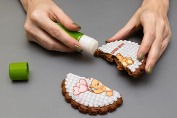 a female hand holds a glue stick and a gingerbread broken in half