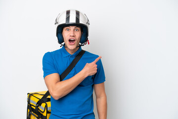 Young caucasian man with thermal backpack isolated on white background surprised and pointing side