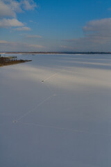 Panorama of the confluence of two rivers. Winter landscape with a frozen big river and a fisherman...