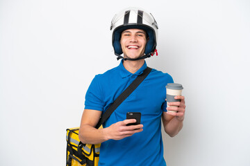 Young caucasian man with thermal backpack isolated on white background holding coffee to take away and a mobile