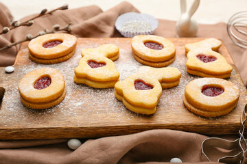 Board with delicious Easter cookies on light background, closeup