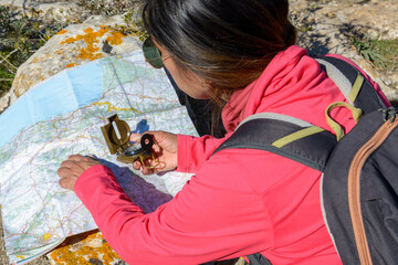 Young hikers sitting on the ground looking at an old map with a compass. Hiking couple in nature,