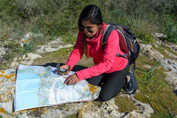 Young hikers sitting on the ground looking at an old map with a compass. Hiking couple in nature,