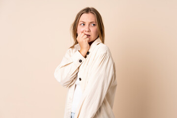 Teenager Ukrainian girl isolated on beige background is a little bit nervous