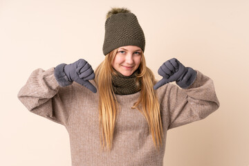 Teenager Ukrainian girl with winter hat isolated on beige background proud and self-satisfied