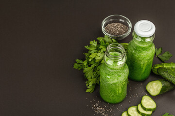 Green smoothie with cucumber in glass bottles. Fresh ripe vegetables, greens, and chia seeds