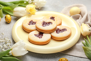 Plate with tasty Easter cookies and spring flowers on table, closeup